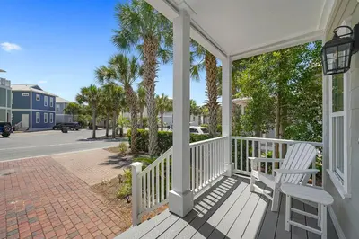 a porch with a chair and palm trees on a street at Southern Charm - Luxury Vacation Rental Near the Beach with Community Pool & Amenities in Seacrest