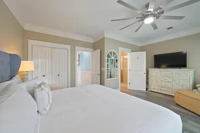 a bedroom with a white bed and a flat screen tv at Southern Charm - Luxury Vacation Rental Near the Beach with Community Pool & Amenities in Seacrest