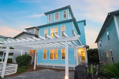 a blue house with a white pergola in front of it at The Sassy Seagull - 30A Beach House with Ocean Views in Seacrest