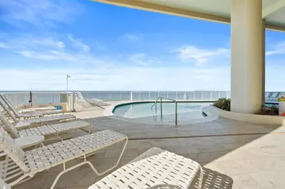 a patio with a pool and chairs and the ocean at Palazzo Beach Resort by Panhandle Getaways in Panama City Beach