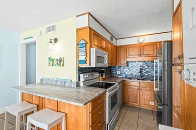 a kitchen with wooden cabinets and stainless steel appliances at Summit 1417 Beach Resort - Amazing Balcony Views in Panama City Beach