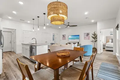 a kitchen and living room with a table and chairs at Beach House with Private Pool - Sunny Sands by Panhandle Getaways in Panama City