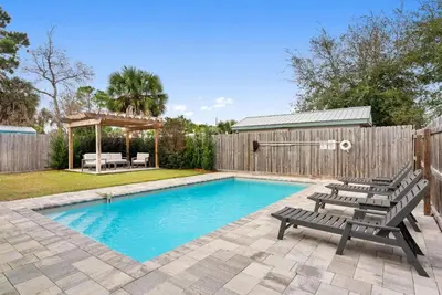 a swimming pool with two benches and a wooden fence at Beach House with Private Pool - Sunny Sands by Panhandle Getaways in Panama City