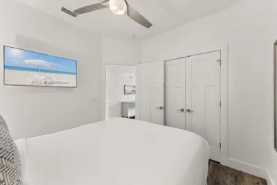 a white bedroom with a bed and a ceiling fan at Beach House with Private Pool - Sunny Sands by Panhandle Getaways in Panama City