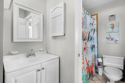 a bathroom with a sink and a toilet and a mirror at Summit 807 Beach Resort - Amazing Balcony Views in Panama City Beach
