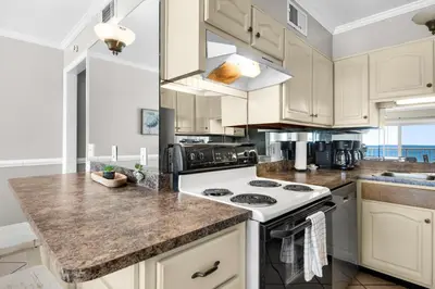 a kitchen with white cabinets and a stove top oven at Summit 807 Beach Resort - Amazing Balcony Views in Panama City Beach