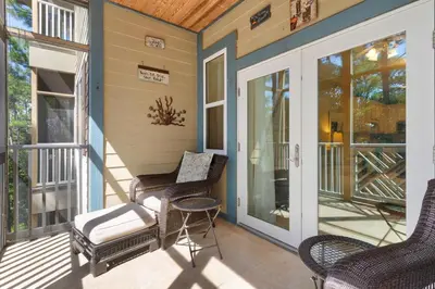 a screened porch with wicker chairs and a door at 30A-Sea La Vie-Seagrove Highlands 2302 in Santa Rosa Beach
