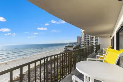 a balcony with a table and chairs and the beach at Commodore 0601 in Panama City Beach