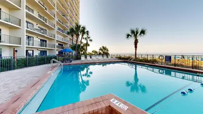 a swimming pool in front of a building with the ocean at Commodore 0601 in Panama City Beach