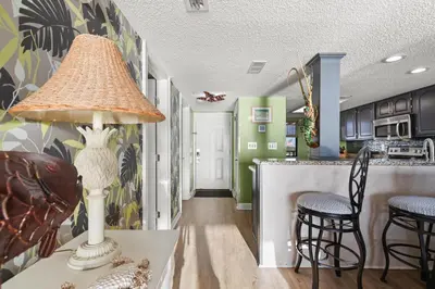 a kitchen with green walls and a table with a lamp at Commodore 0601 in Panama City Beach