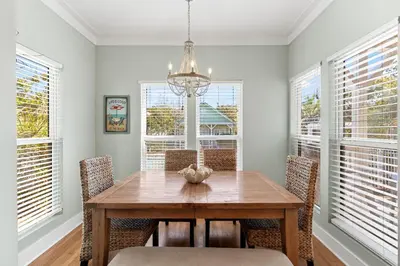 a dining room with a table and chairs and windows at Beach Therapy in Seacrest