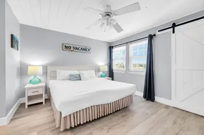 a white bedroom with a bed and a ceiling fan at Lullwater Beach 415 in Panama City Beach