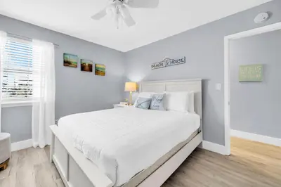 a bedroom with a large white bed with a ceiling fan at Lullwater Beach 415 in Panama City Beach