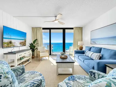 a living room with a blue couch and a view of the ocean at Edgewater Tower 3-1003 in Panama City Beach
