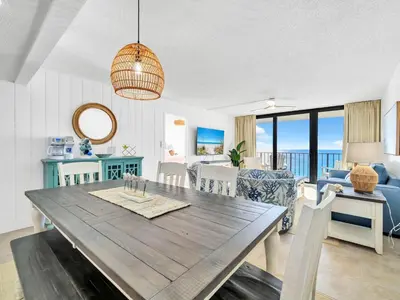 a dining room and living room with a table and chairs at Edgewater Tower 3-1003 in Panama City Beach