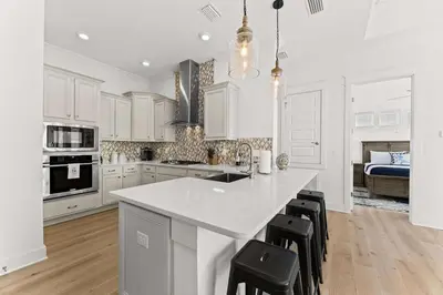 a kitchen with white cabinets and a large island with stools at Rhema Luxury Beach Haus 2BR 2B ResortPool with optional 6-seater GolfCart & 4Bikes in Inlet Beach