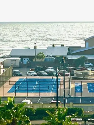 a tennis court next to a large body of water at PCB Beach Gateaway On The Sand in Panama City Beach