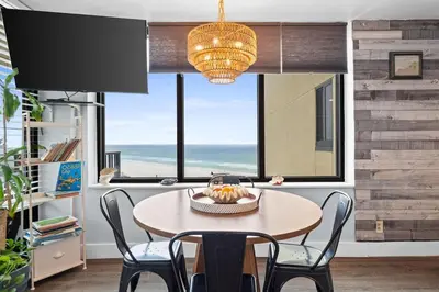 a dining room with a table with chairs and a chandelier at PCB Beach Gateaway On The Sand in Panama City Beach