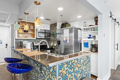 a kitchen with a counter with blue stools at PCB Beach Gateaway On The Sand in Panama City Beach