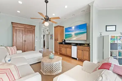 a living room with white furniture and a flat screen tv at High Tide in Inlet Beach