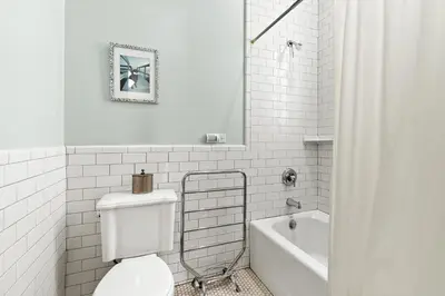 a white bathroom with a toilet and a bath tub at High Tide in Inlet Beach