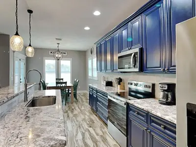 a kitchen with blue cabinets and a dining room at Nothin But Time in Panama City Beach