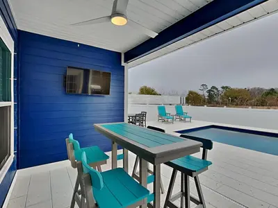 a patio with a table and chairs and a swimming pool at Nothin But Time in Panama City Beach