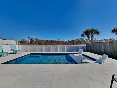 a swimming pool with two chairs next to a fence at Nothin But Time in Panama City Beach
