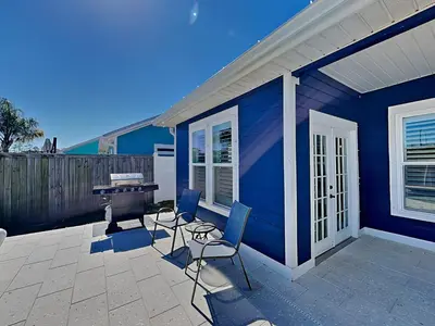 a blue house with chairs and a grill on a patio at Nothin But Time in Panama City Beach