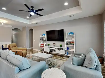 a living room with two couches and a flat screen tv at Nothin But Time in Panama City Beach