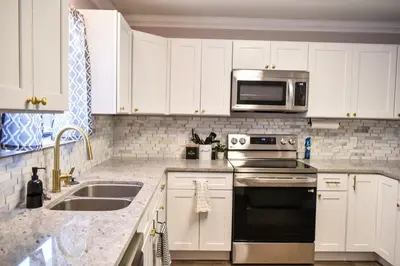 a kitchen with white cabinets and a stove and microwave at Renovated Townhome by the Bay in Panama City