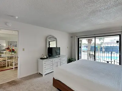 a bedroom with a bed and a television and a balcony at Edgewater Villa #2713 - The Palm and Pool Villa in Panama City Beach