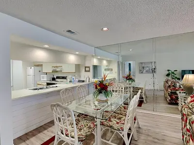 a dining room with a table and chairs and a kitchen at Edgewater Villa #2713 - The Palm and Pool Villa in Panama City Beach