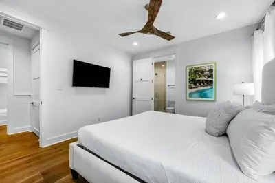 a white bedroom with a bed and a flat screen tv at Sunny Side Up by Travel Life Vacations in Santa Rosa Beach