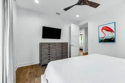 a white bedroom with a bed and a flat screen tv at Sunny Side Up by Travel Life Vacations in Santa Rosa Beach