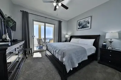 a bedroom with a large bed and a balcony at Ocean Ritz 2202 by Emerald Coast Retreats in Panama City Beach