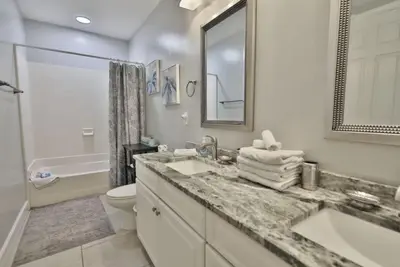 a bathroom with a sink and a toilet and a mirror at Ocean Ritz 2202 by Emerald Coast Retreats in Panama City Beach
