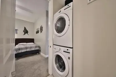 a laundry room with a washer and dryer next to a bed at Ocean Ritz 2202 by Emerald Coast Retreats in Panama City Beach