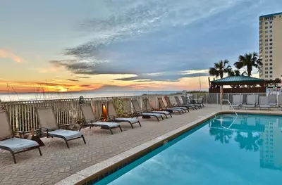 a hotel swimming pool with chairs and the ocean at Ocean Ritz 2202 by Emerald Coast Retreats in Panama City Beach