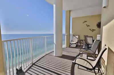a balcony with chairs and a cat looking at the ocean at Ocean Ritz 2202 by Emerald Coast Retreats in Panama City Beach