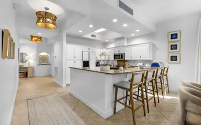 a kitchen with white cabinets and a bar with stools at Sunset Oasis on 30A in Rosemary Beach