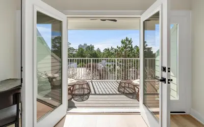a glass door leading to a balcony with a table and chairs at Sunny Cove in Santa Rosa Beach