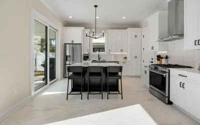 a kitchen with white cabinets and black bar stools at Sunny Cove in Santa Rosa Beach