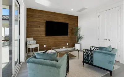 a living room with two chairs and a tv on a wall at Magnolia Way in Santa Rosa Beach