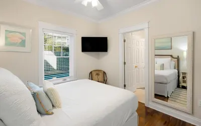 a white bedroom with two beds and a mirror at Bluesunshine in Santa Rosa Beach
