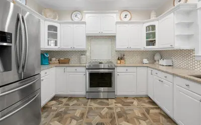a kitchen with white cabinets and a stainless steel refrigerator at Bluesunshine in Santa Rosa Beach