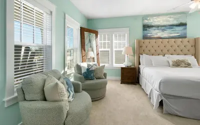 a bedroom with a bed and a chair and windows at Bluesunshine in Santa Rosa Beach