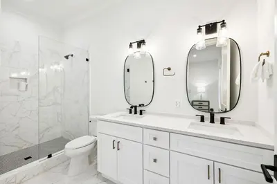 a white bathroom with a toilet and two mirrors at Gather at the Gulf in Inlet Beach