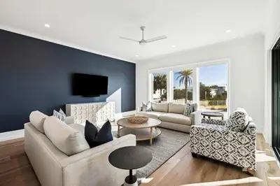 a living room with a couch and chairs and a tv at Gather at the Gulf in Inlet Beach