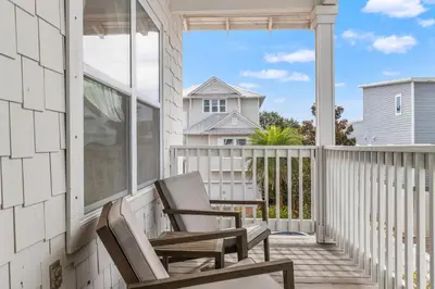 two chairs on a porch with a view of a house at 30A Beach House with Golf Cart - Whatcha Dune in Inlet Beach